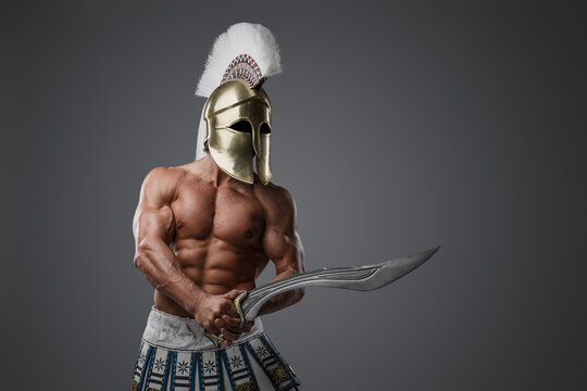 Portrait of shirtless greek soldier from past with strong body holding sword.