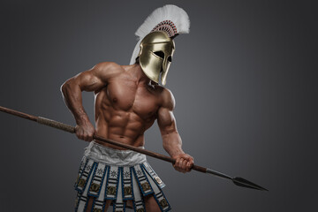 Shot of greek athlete with perfect body and spear dressed in plumed helmet.