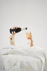 a woman in bed with a bottle of champagne. without face