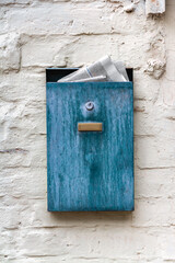 A blue box with a newspaper on a plastered old wall. Nastalgia.