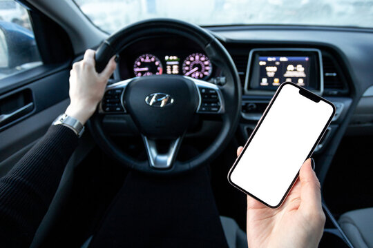 A Girl Driving A Hyundai With An IPhone 14 In Her Hand