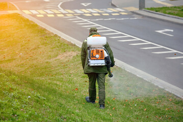Man spray poison from mites, mosquitoes, ticks and pests. Worker with backpack mistblower spraying...