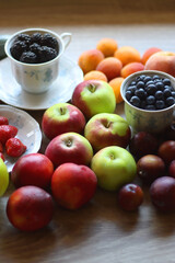 Berries in vintage porcelain dishes, other healthy fruit and vegetable on wooden table. Selective focus.