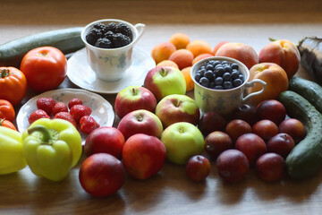Berries in vintage porcelain dishes, other healthy fruit and vegetable on wooden table. Selective focus.