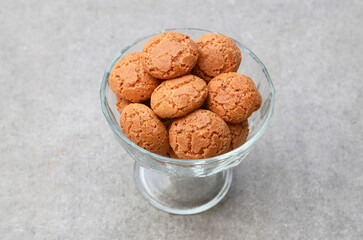 Classic italian almond cookies amaretti  in a glass bowl on a gray background.Famous amarettini cookie biscuits.Delicious Christmas pastry popular in Italy.Selective focus.