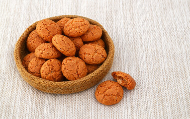 Traditional Italian almond cookies amaretti  in a basket on a linen tablecloth background.Famous amarettini cookie biscuits.Delicious pastry popular in Italy.Selective focus.