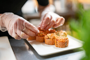 professional chef's hands making sushi roll in a restaurant kitchen