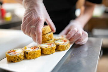 Obraz na płótnie Canvas professional chef's hands making sushi roll in a restaurant kitchen