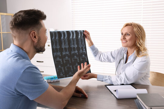 Doctor with MRI image consulting patient in clinic