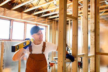 Worker using nail gun to build basement room