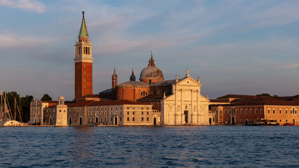 San Giorgio Maggiore is a stunning church located on an island in Venice's lagoon. The church's iconic white facade and towering bell tower provide a striking contrast against blue sky and water.