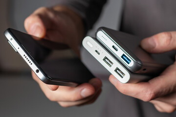 the man is holding the phone and the charger. Powerbank and smartphone in hand.