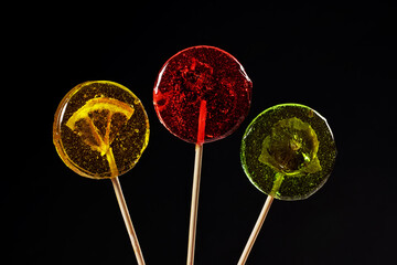 Sweet colorful lollipops with dried fruits on black background