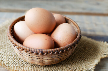 Chicken eggs in a wicker bowl on burlap on a wooden background. Rustic style. The concept of organic food. Horizontal orientation.