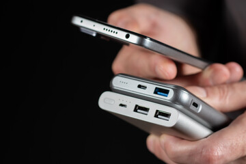 the man is holding the phone and the charger. Powerbank and smartphone in hand.