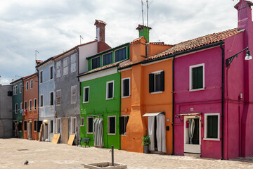 Brightly colored houses in Burano, Venice, Italy. Visitors see a range of colors, incl. vibrant blues, yellows, greens, and pinks, as they explore the island's winding streets and picturesque canals.