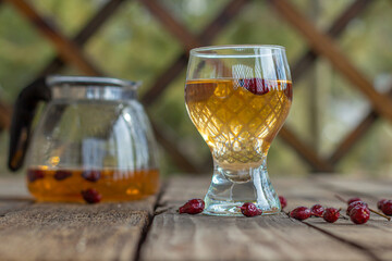Red tea in a transparent cup on a wooden table, rosehip tea, rustic