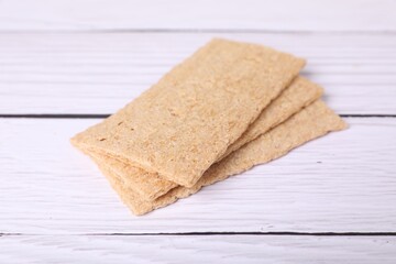 Fresh crunchy rye crispbreads on white wooden table, closeup