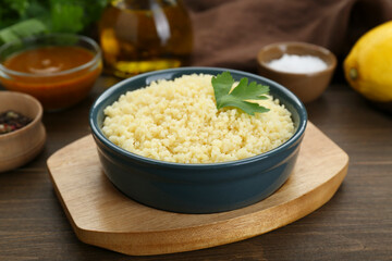 Tasty couscous with parsley on wooden table, closeup