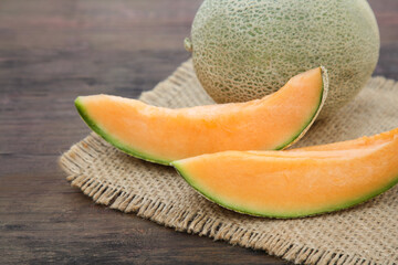 Cut and whole delicious ripe melons on wooden table, closeup