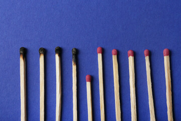 Burnt and whole matches on blue background, flat lay. Stop destruction concept