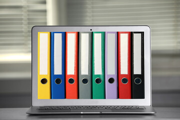 Store and organize information. Modern laptop with hardcover office folders on screen