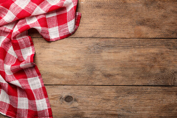 Checkered tablecloth on wooden table, top view. Space for text