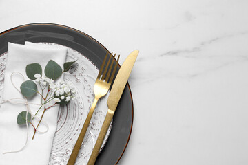 Stylish table setting with cutlery, flower and eucalyptus leaves, top view. Space for text