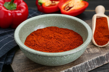 Bowl of aromatic paprika and fresh peppers on black wooden table