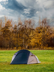 Blue tent on a green grass in a field forest in the background. Travel and tourism concept. Nobody. Active outdoor activity