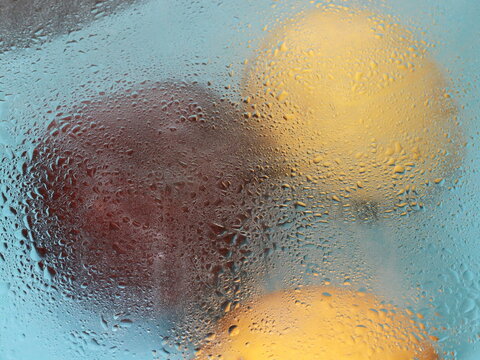 two lemons and a red apple in the rain and water drops abstraction food background