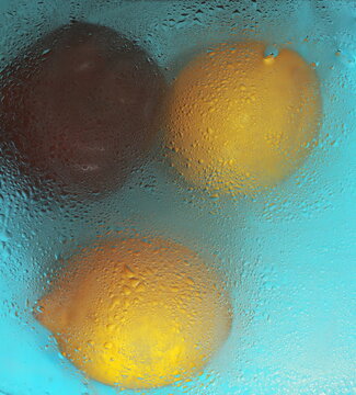two lemons and a red apple in the rain and water drops abstraction food background