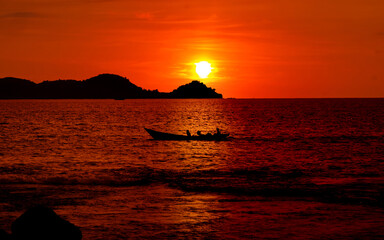 Naklejka na ściany i meble Beautiful ocean sunset panorama with island and fisherman boat in silhouette
