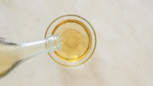 apple cider vinegar is poured from the bottle into a glass bowl.