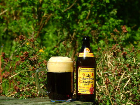 Bottle of Aech Schlenkerla Rauchbeer specialty smoked craft beer on table in early spring garden - Taldom, Russia - May 17, 2019