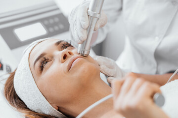 Electroporation without injection mesotherapy. Woman cosmetologist performs cosmetic procedure on...