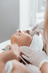 Obraz na płótnie Canvas Electroporation without injection mesotherapy. Woman cosmetologist performs cosmetic procedure on skin of the face to reduce wrinkles, restore, regenerate and rejuvenate the girls face. Beauty clinic