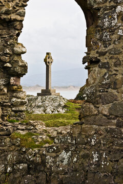 View of the Celtic Cross on Llanddwyn Island through the ruins of the Church of St Dwynwen, Newborough, North Wales
