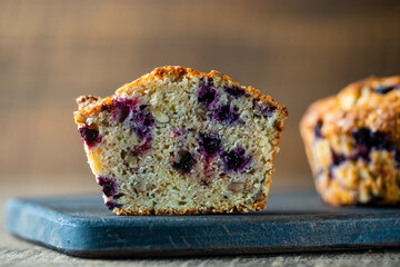 Half muffin with blueberries and walnuts on wooden table, closeup. Sweet pastries on the board. Fresh cupcakes for breakfast