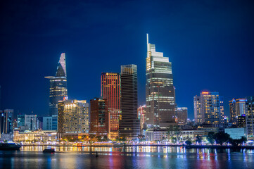 Naklejka premium Amazing view of urban city with luminous skyscrapers and road with traffic placed near rippling river at night