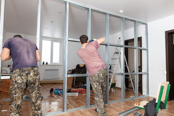 A man installs a metal profile for a wall in a room.