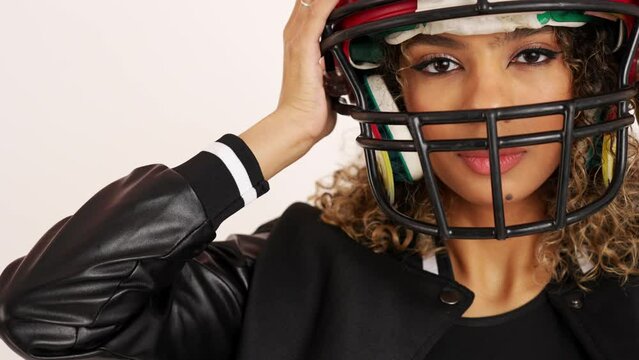 Close shot of a young woman wearing an American football helmet on white background. High quality 4k footage