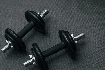 Obraz na płótnie Canvas Fitness background. Two 10 kg dumbbells on a gray mat. Sports concept - gray mat, two black dumbbells 10 kg