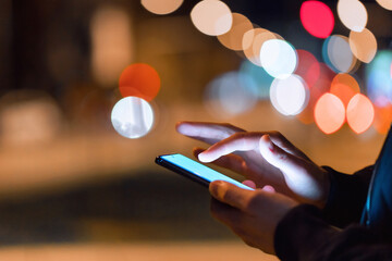 Close-up shot of a man using a phone in the city at night.