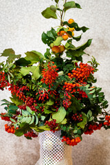 Beautiful autumn bouquet of rowan branches with red berries and branches with small decorative apples