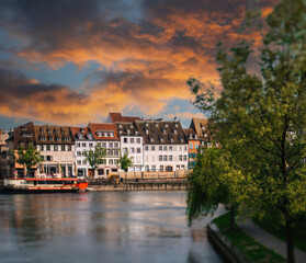 Obraz premium Strasbourgs Rustic River Cityscape at Sunset with beautiful ill river and boats - majestic timbered Alsatian houses in background - red sunset