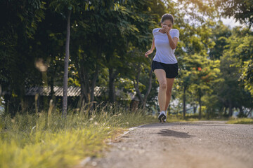 Silhouette of young woman running sprinting on road. Fit runner fitness runner during outdoor workout.