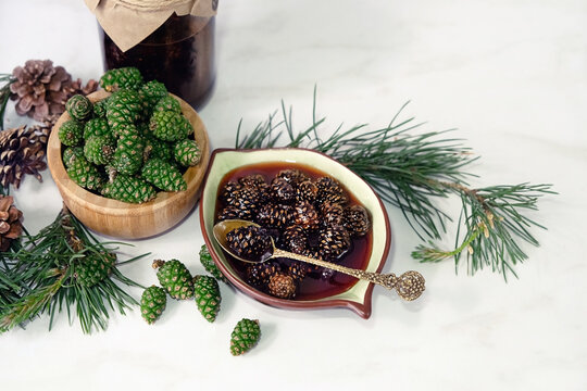 Jam from young pine cones and green cones in bowls on table. healthy plants of folk medicine containing vitamin C, used for the treatment of colds, strengthening immunity. organic anti-cold remedy.
