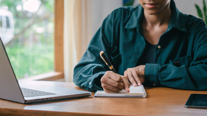 take notes in a notebook, African American housewife looking at family grocery store income and expenditures and calculate household expenses , insurance, water, electricity