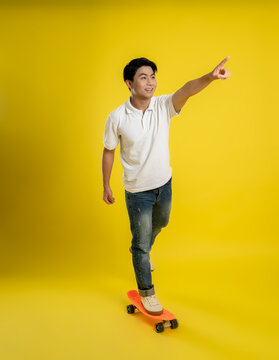 image of young asian male playing skateboard on a yellow background